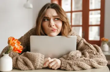 woman sat at a table looking confused