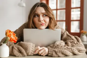 woman sat at a table looking confused