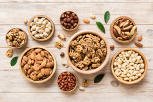 Eight wooden bowls of nuts and seeds on a wooden table.