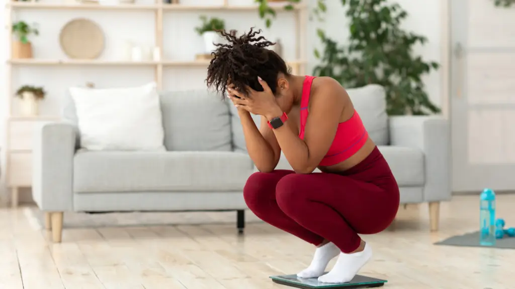 woman crouched down on scales looking upset