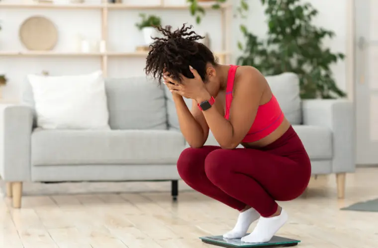 woman crouched down on scales looking upset