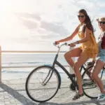 2 woman riding a bike on a costal path