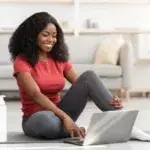 best online weight loss coach: picture of a woman sat on the floor smiling at a laptop.